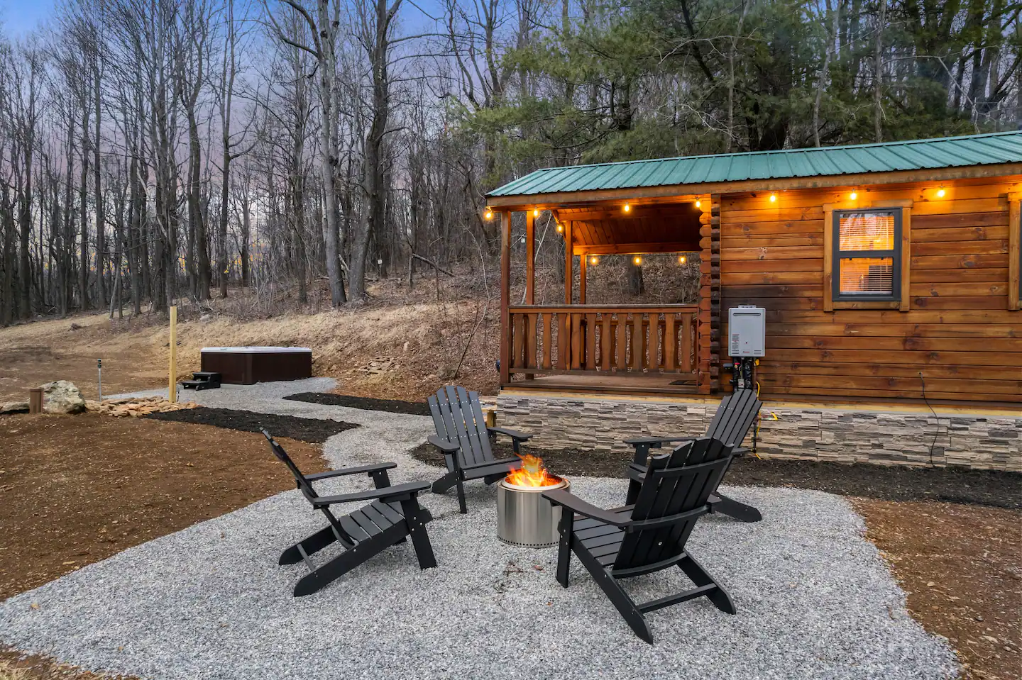 Log cabin at dusk with string lights and a fire pit