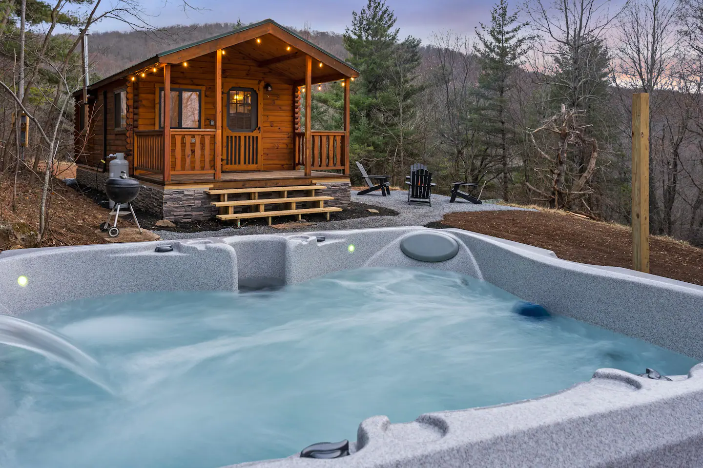Log cabin with a hot tub and a mountain treeline