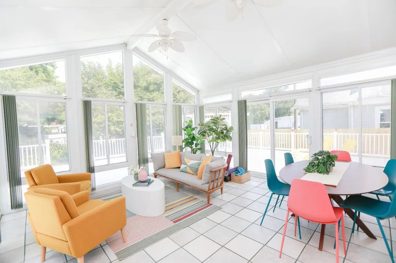 Light filled sunroom with lounge area and 6-person dining table