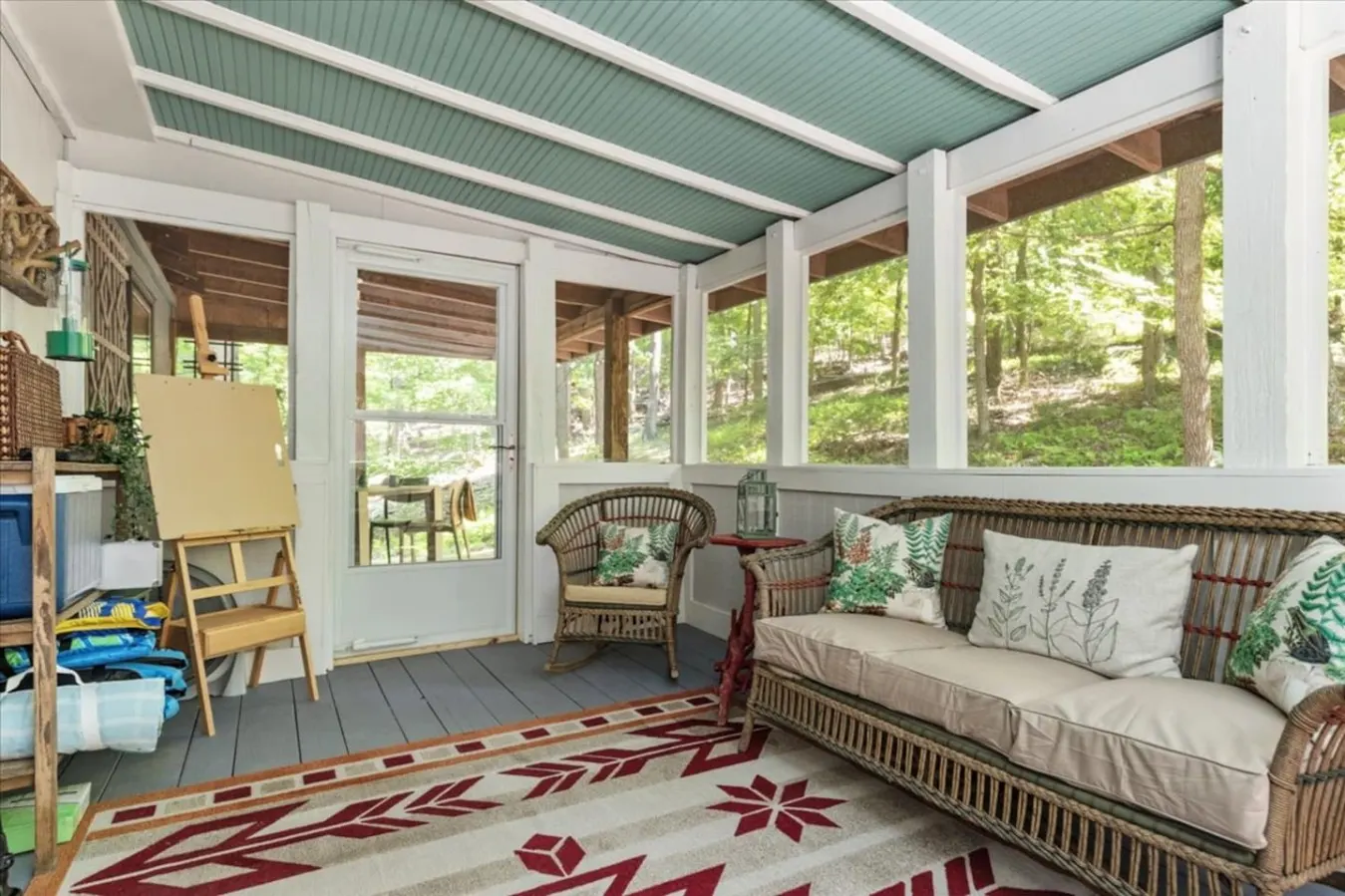 The screened area has a large comfy chair, couch, and rocking chair to gather and hang in comfort. The screened in porch is also the storage location for outdoor gear and supplies.