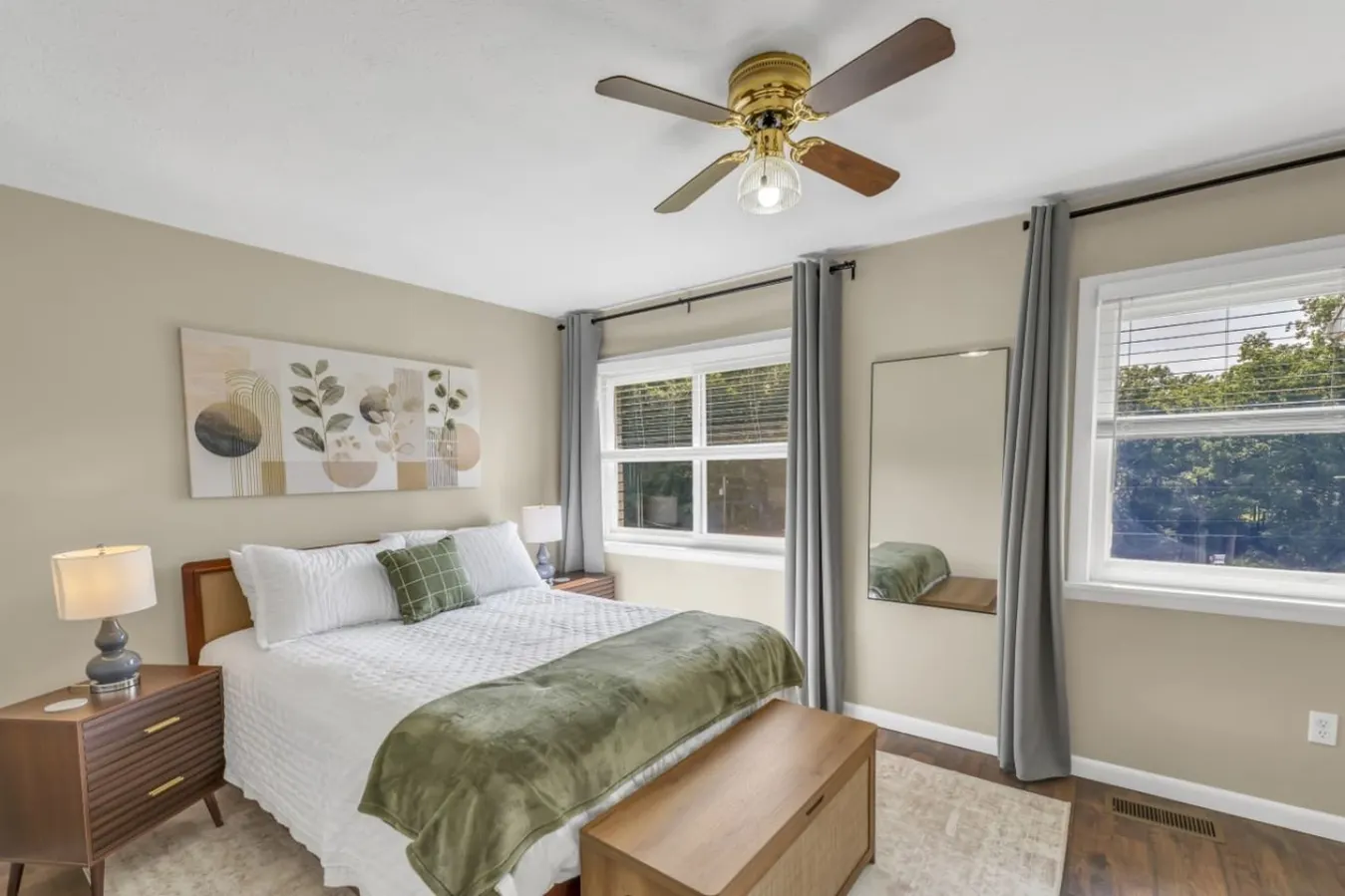 A bright queen room with the woods just outside the window.